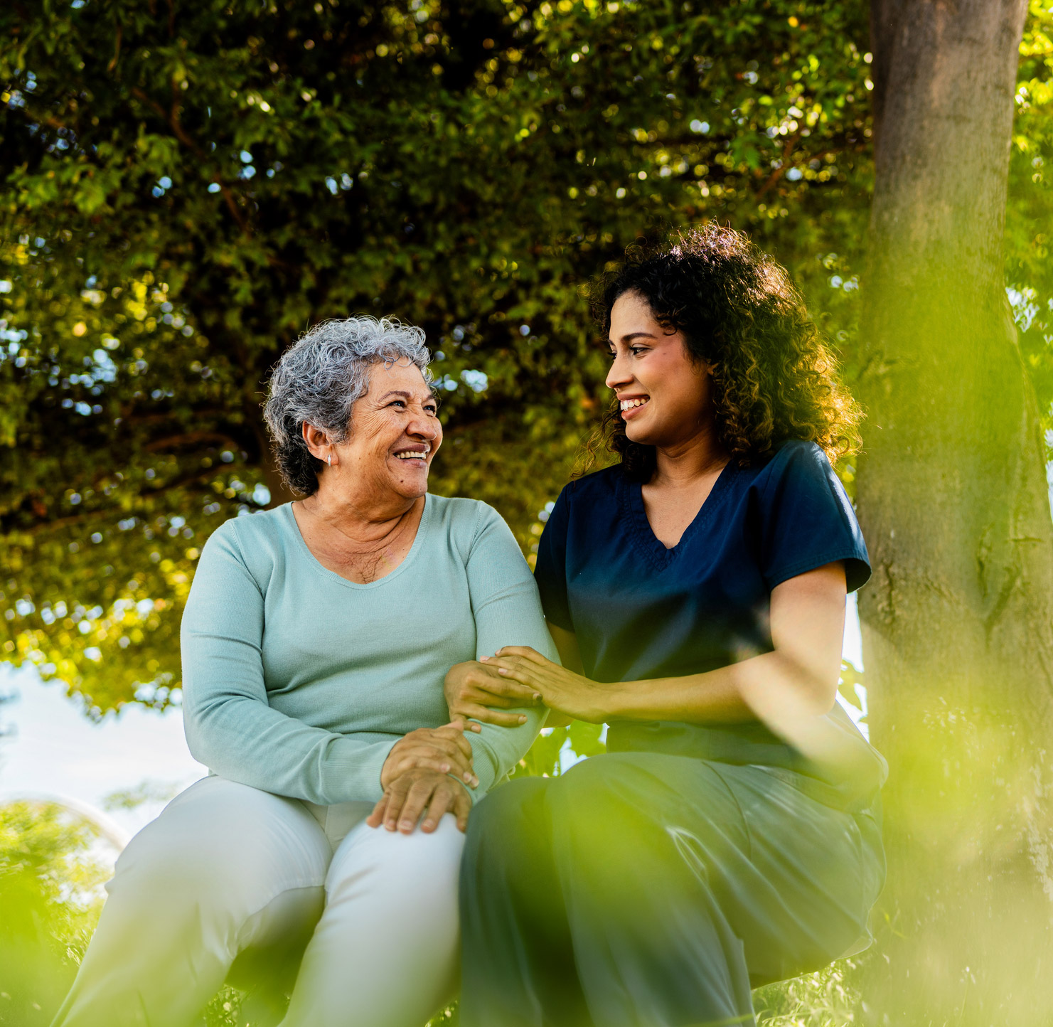 Caregiver and senior woman smiling outdoors together