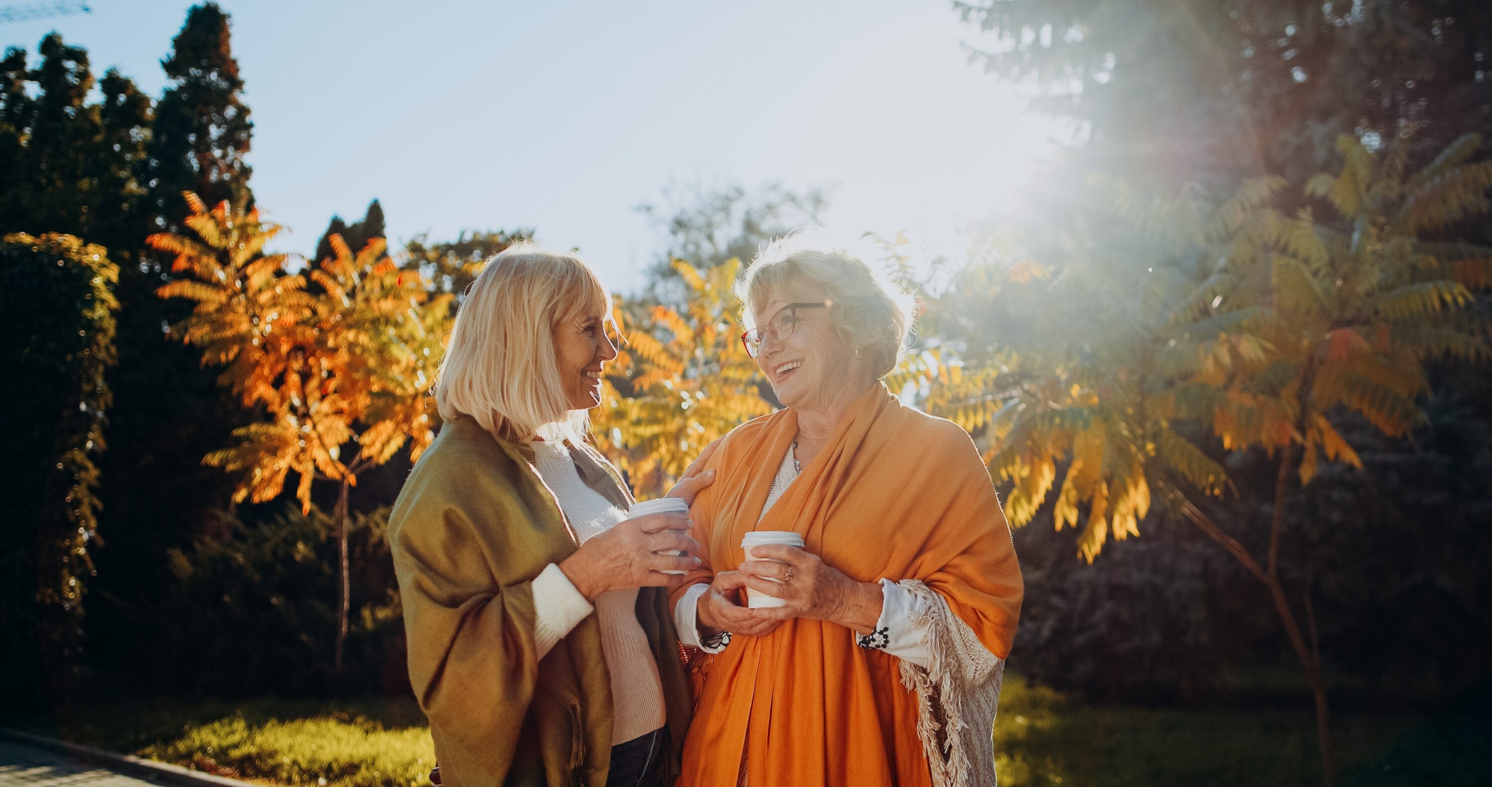 Two women enjoying coffee outdoors in autumn
