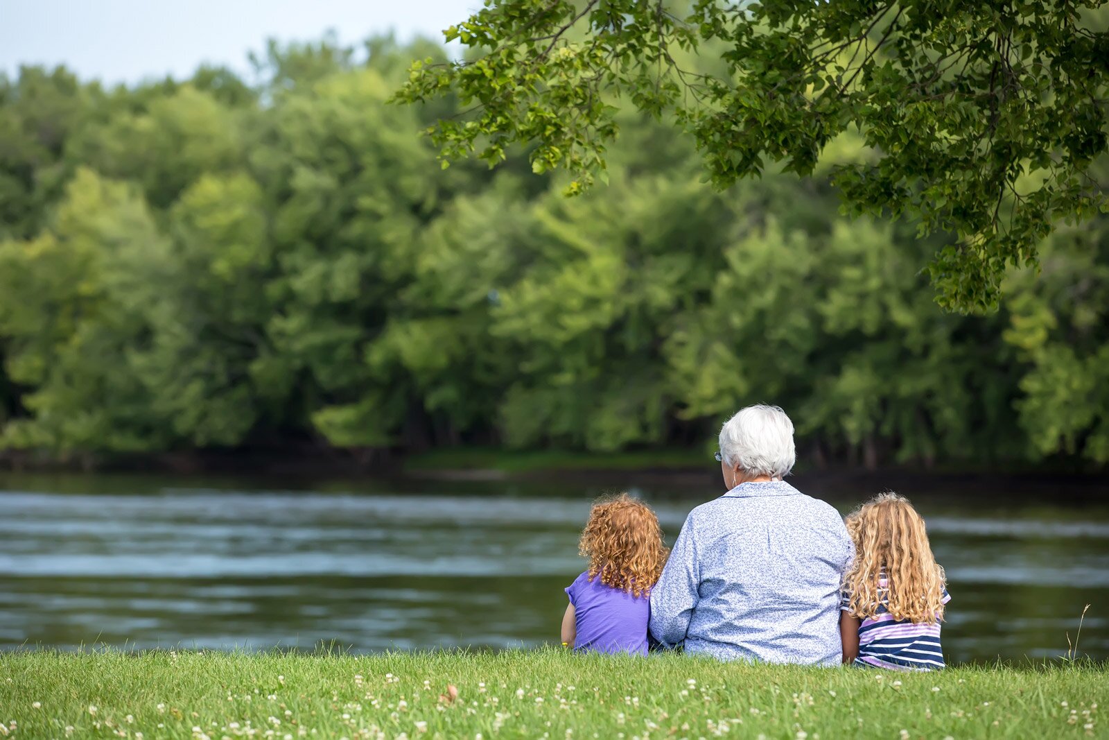 Grandparent with two children by riverside