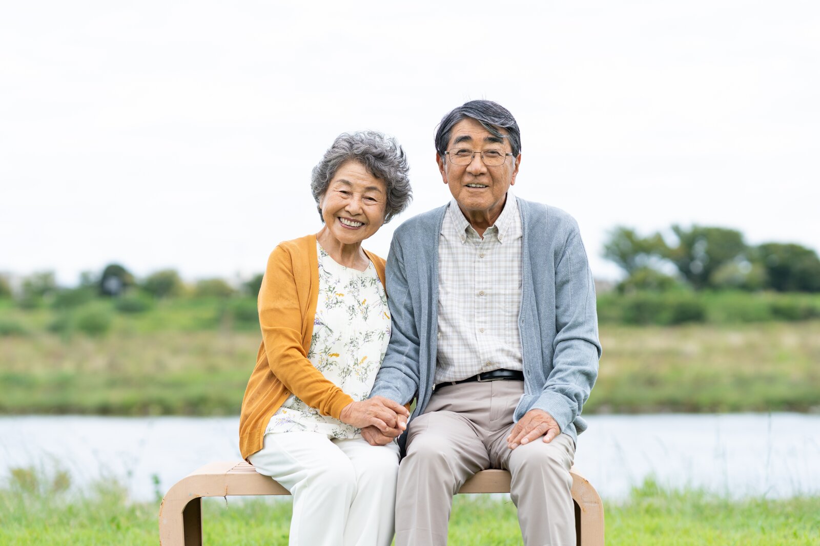 Smiling elderly couple holding hands on park bench