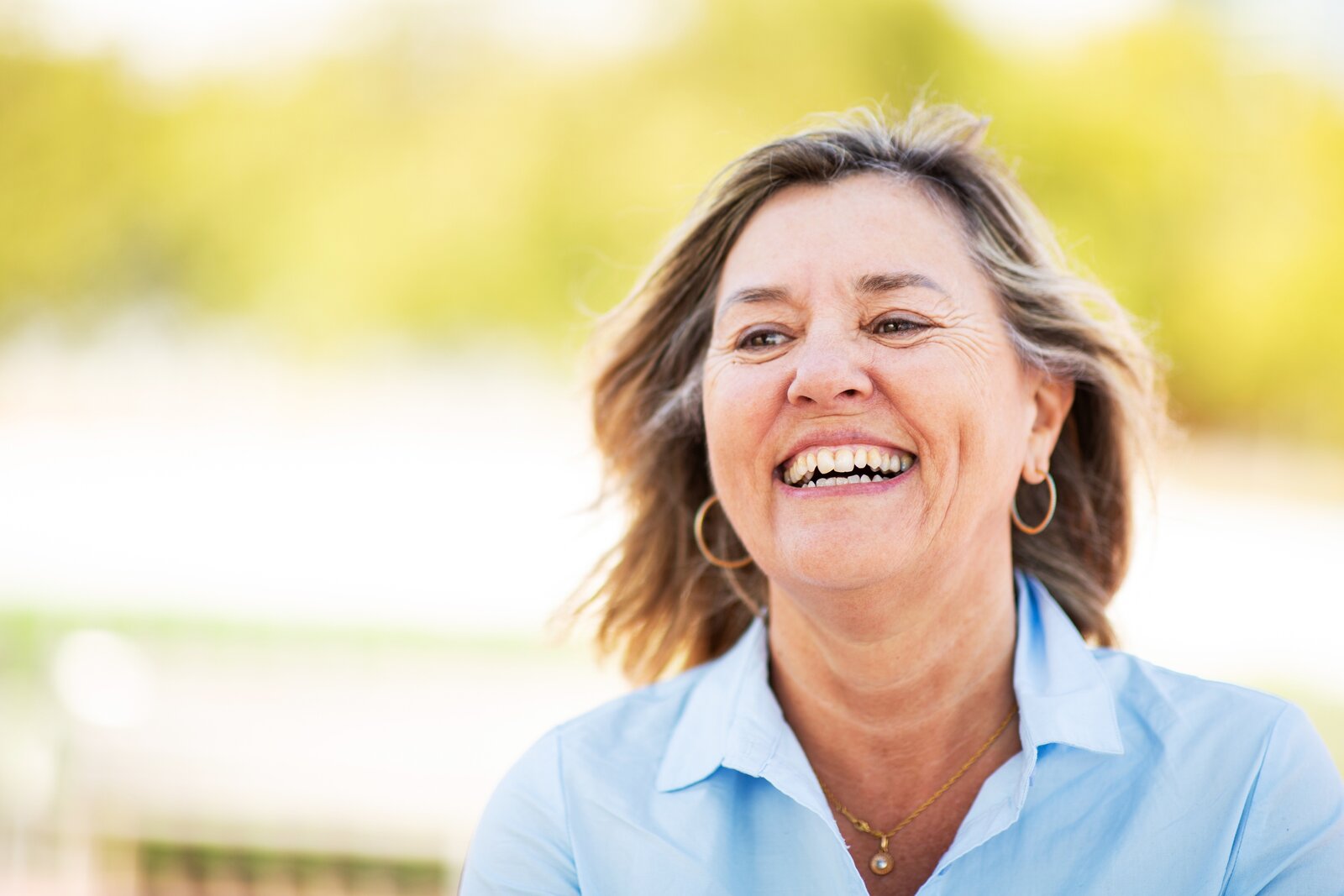 Smiling middle-aged woman outdoors in sunlight