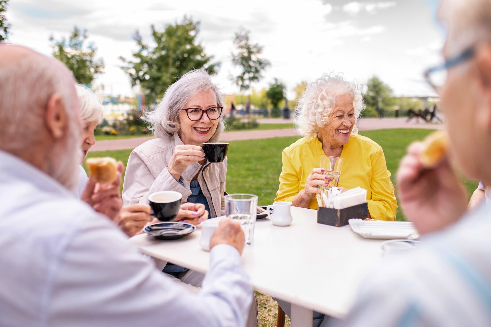 Seniors enjoying coffee together outdoors in park