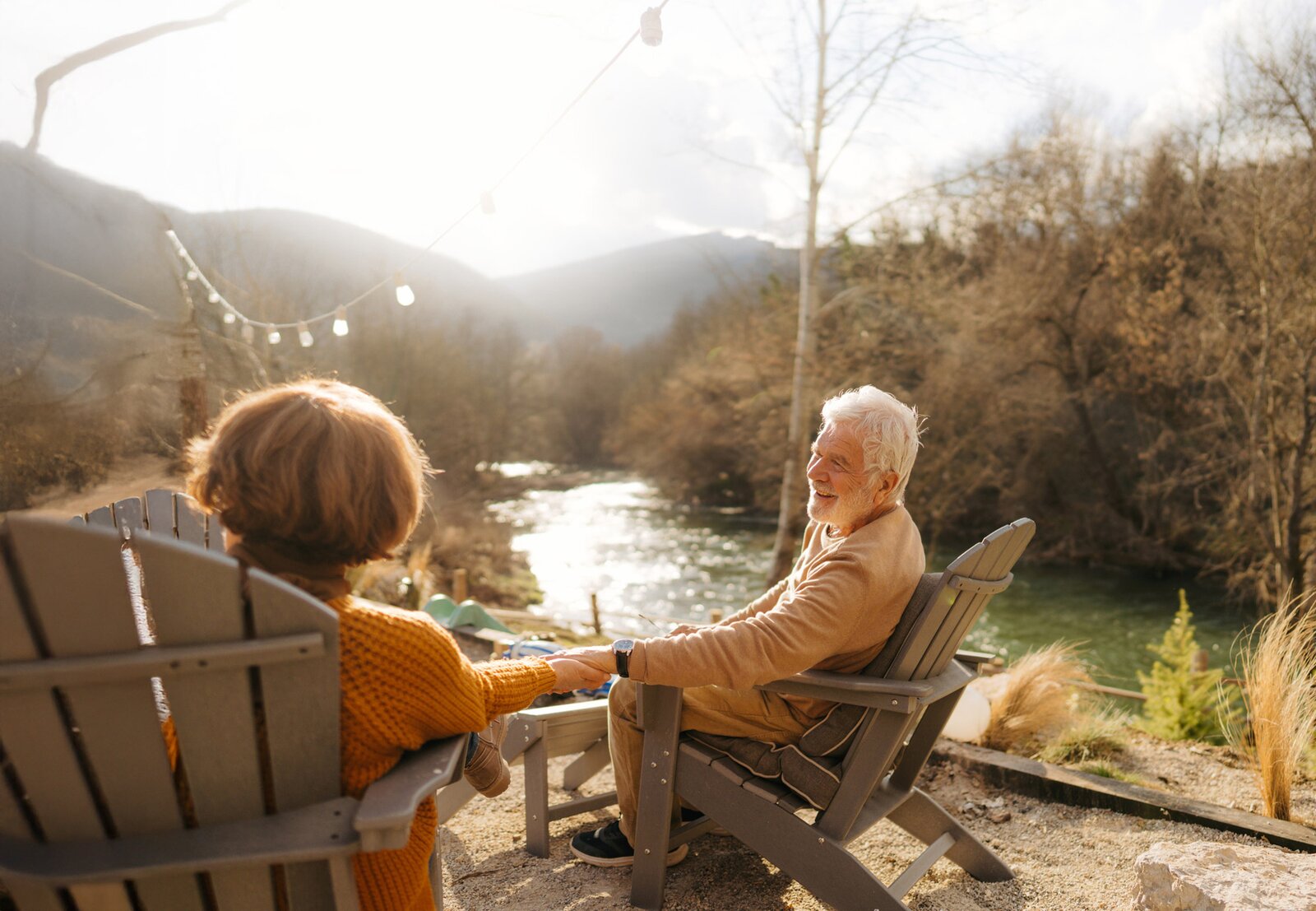 Senior couple holding hands by riverside at sunset