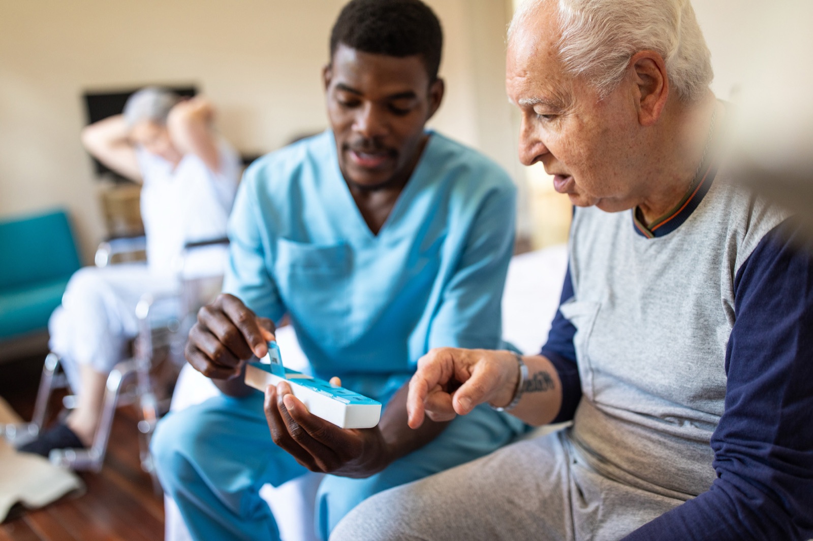 Nurse teaching elderly man to use medical device
