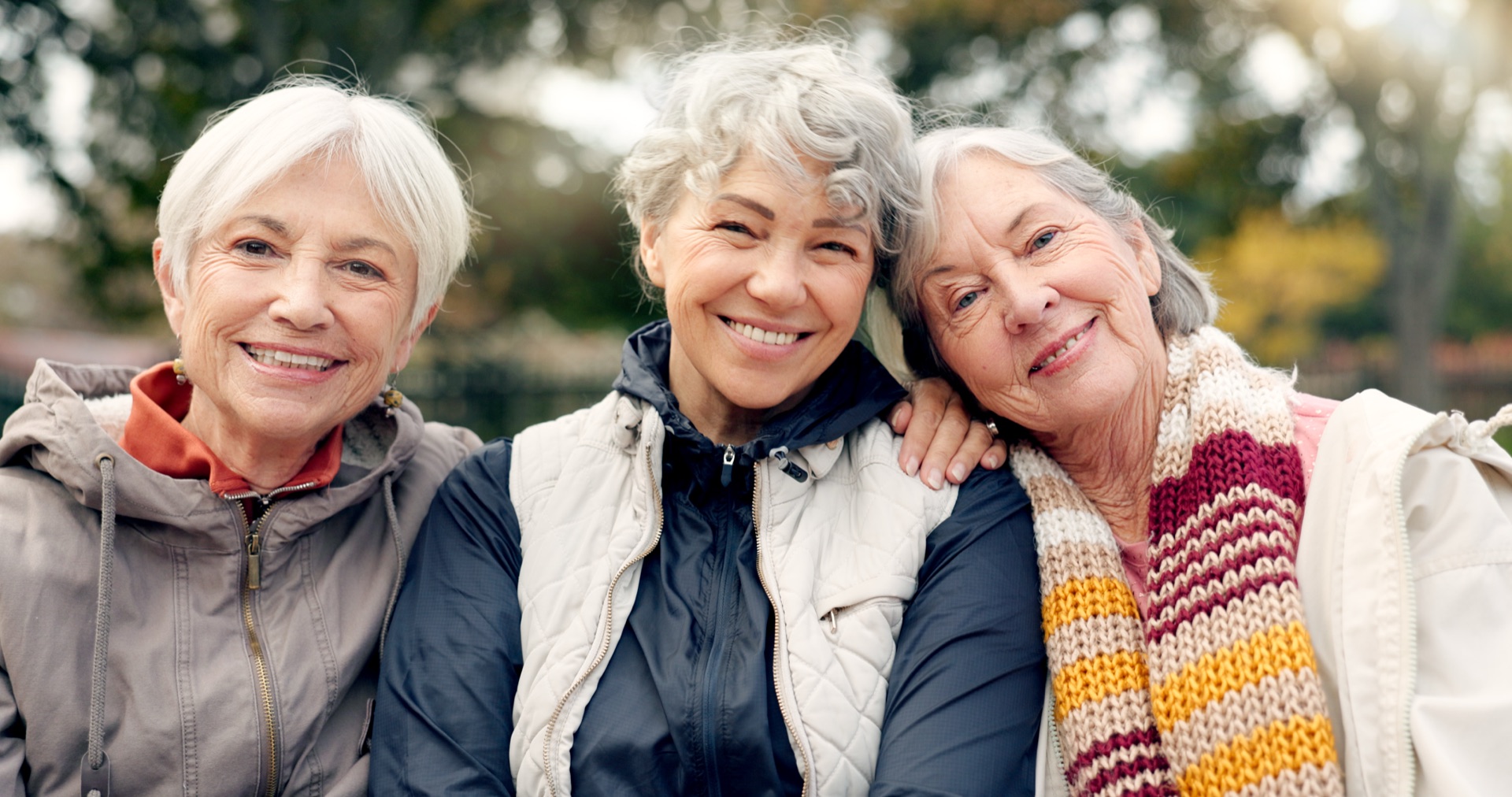 Three elderly women smiling outdoors together