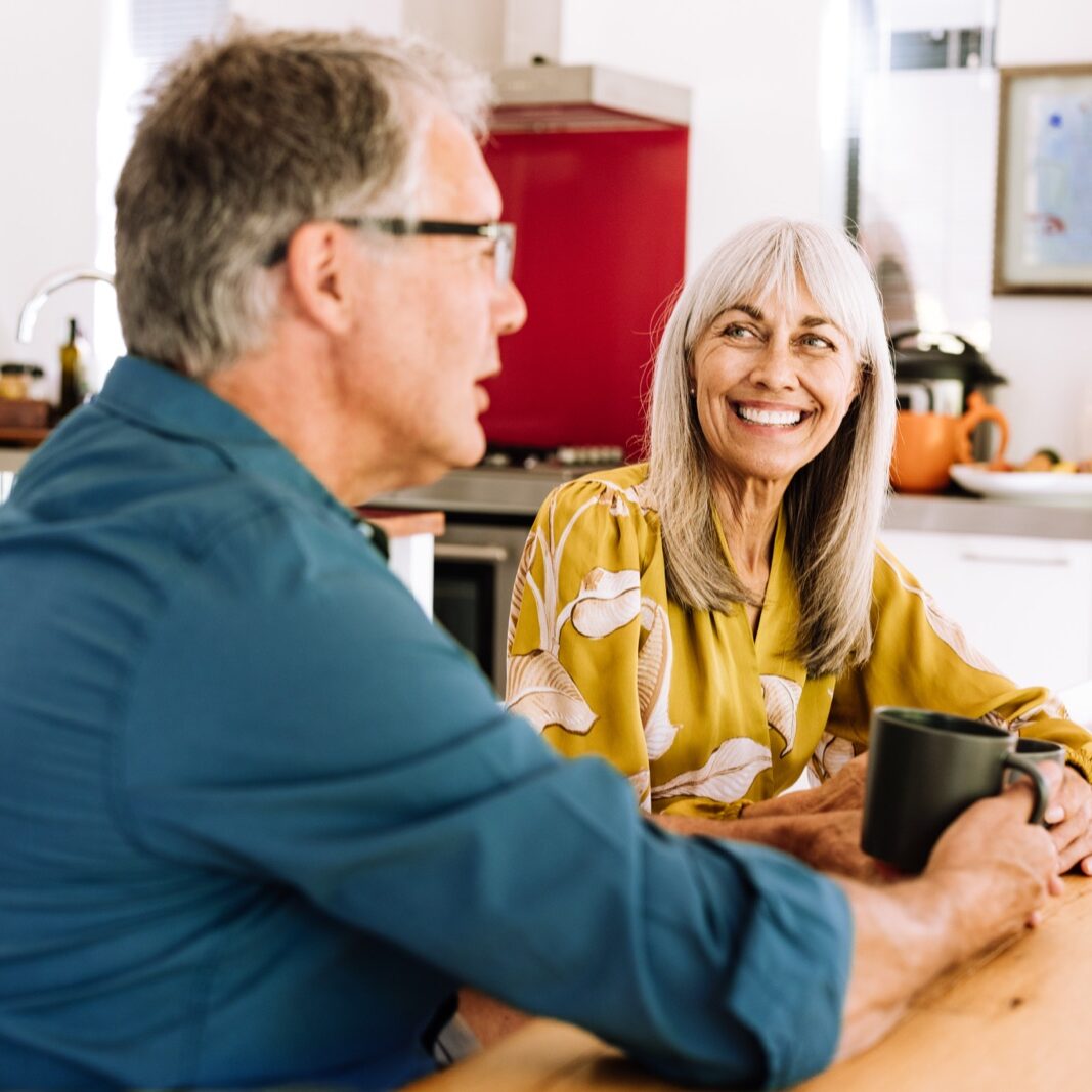 Older couple chatting over coffee in bright kitchen