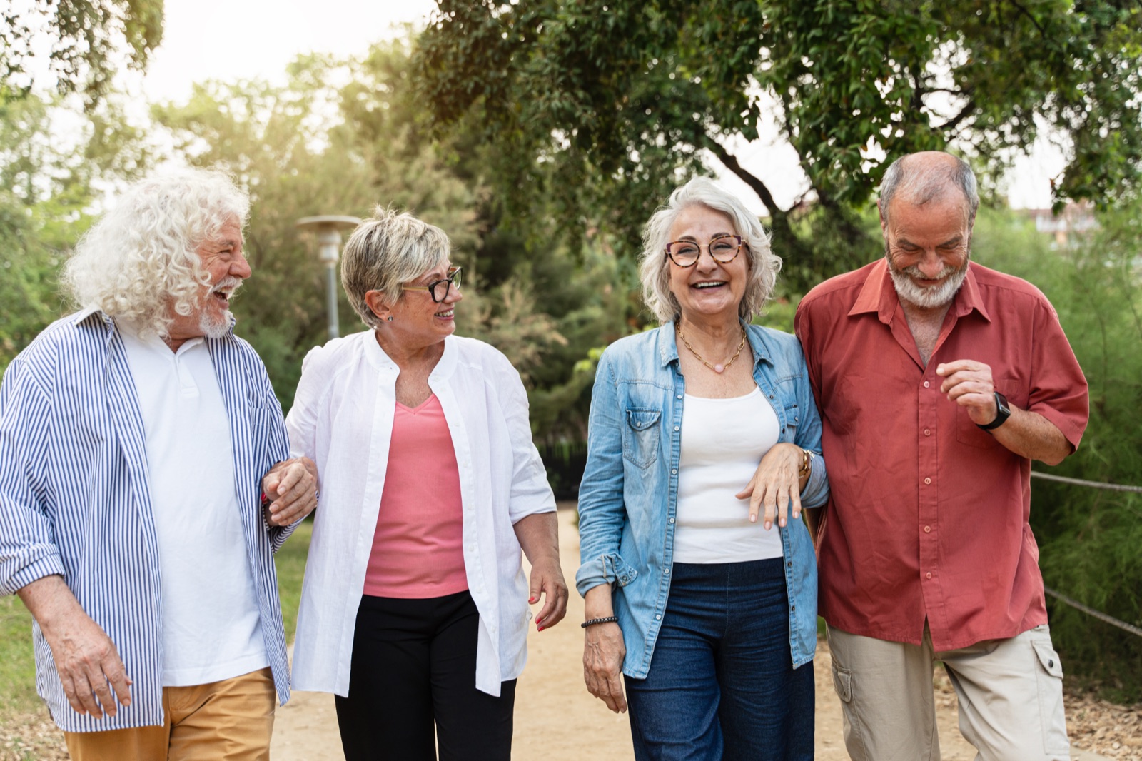 Four seniors walking and laughing in park