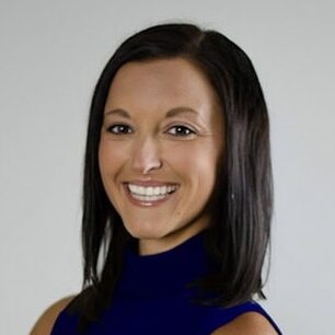 Smiling woman in blue sleeveless top, arms crossed