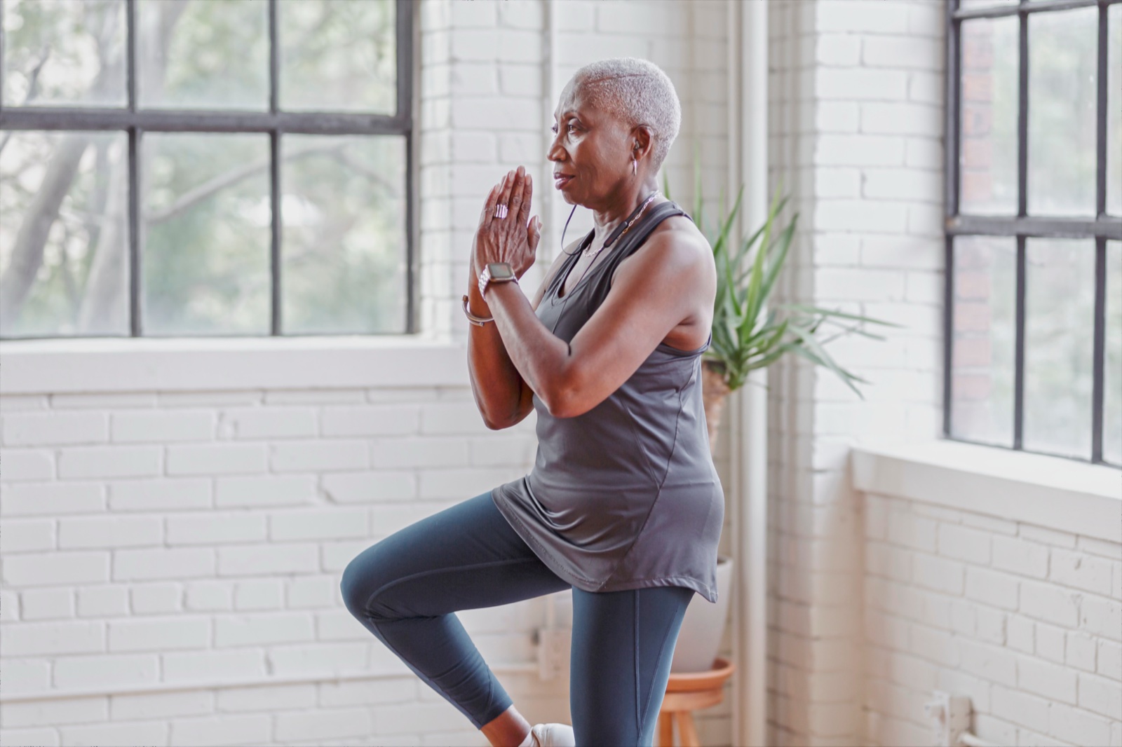 Older woman practicing tree pose indoors